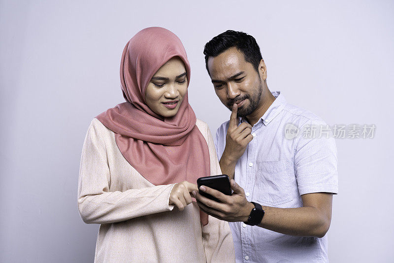 年轻的亚洲马来夫妇在手机上分享信息