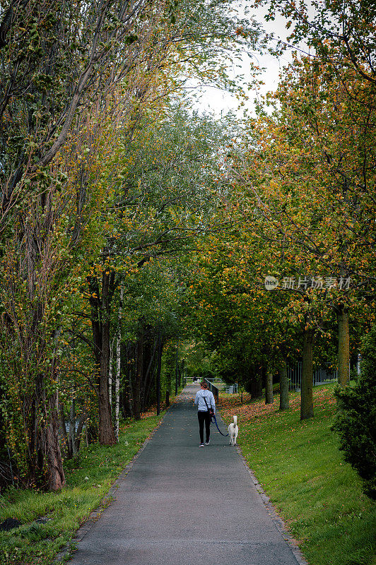 图为一位女士和一只狗在列支敦士登首都瓦杜兹郊区的公园里散步