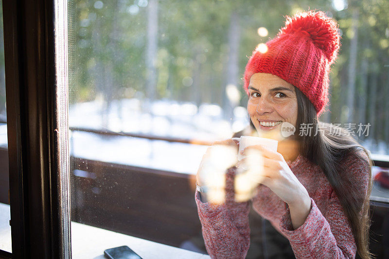 一个年轻漂亮的女人在滑雪胜地的阳台上喝咖啡