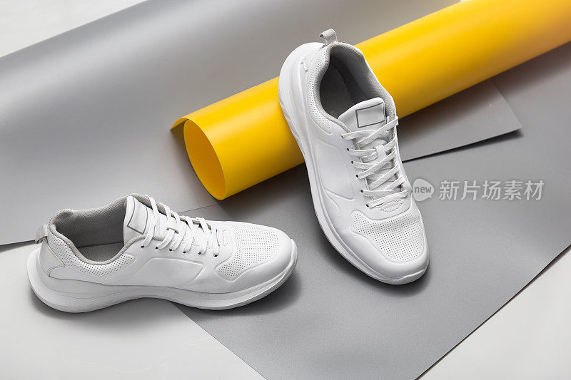 时尚的白色帆布鞋在灰色和黄色的背景
