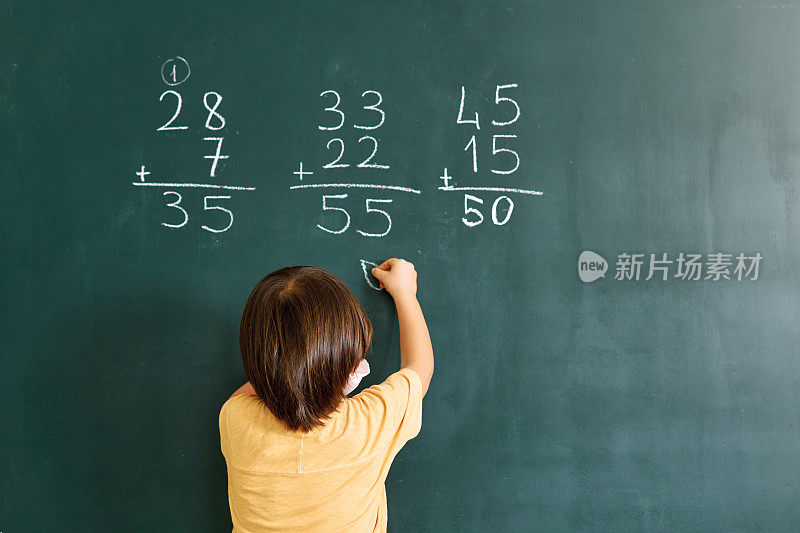 可爱的孩子在黑板上写数学。回到学校