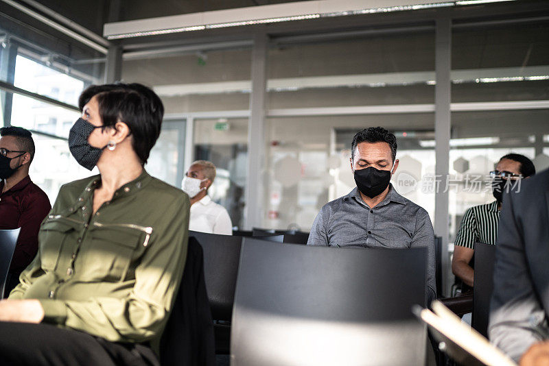 商务人士参加研讨会时要保持社交距离并戴上口罩
