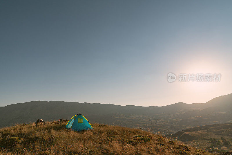 露营椅和帐篷在日落在山顶的自然