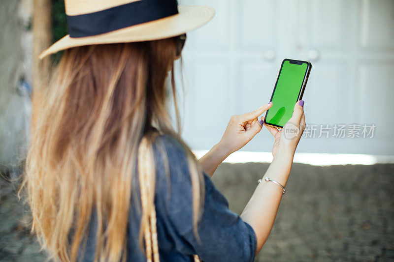 智能女人的手握和触摸手机智能手机与色度键绿色屏幕在城市背景