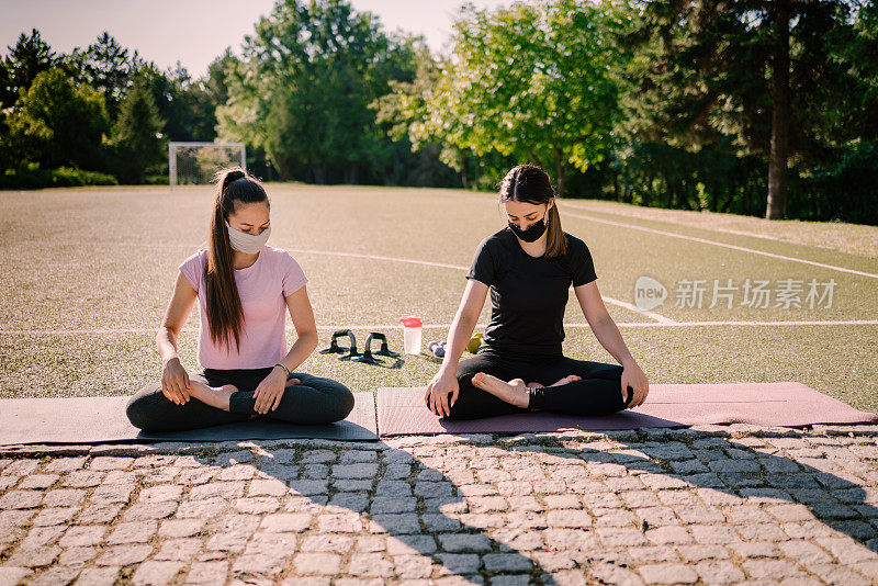 运动的年轻女子坐在垫子上沉思在早上。运动期间covid