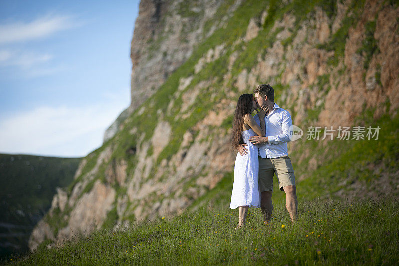 年轻的成年夫妇在山坡上亲吻