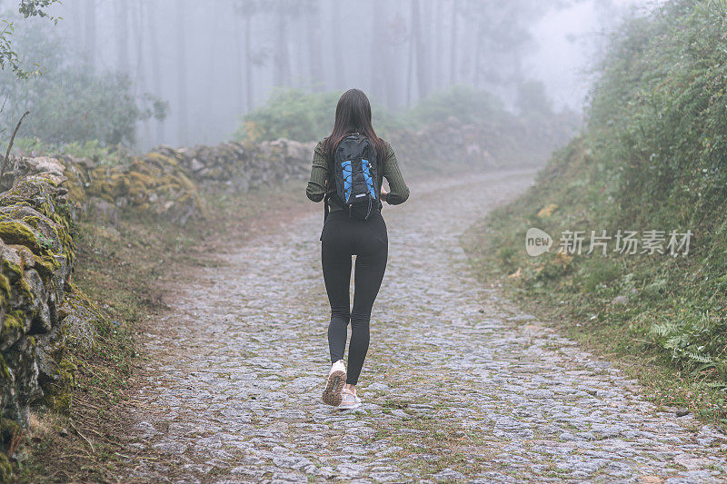 背着背包的年轻女子徒步旅行者在户外的山区旅行