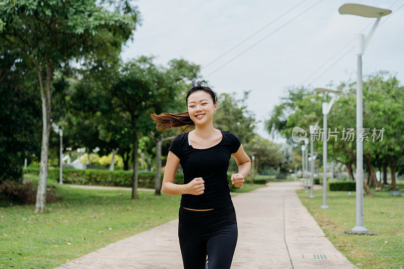 快乐的年轻亚洲女人在早上在公园跑步