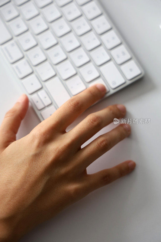 女性的手在白色的电脑键盘上打字