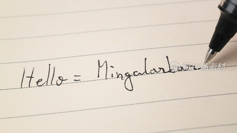 缅甸语初学者在笔记本微距镜头上写着“你好单词Mingalarbar”作为家庭作业