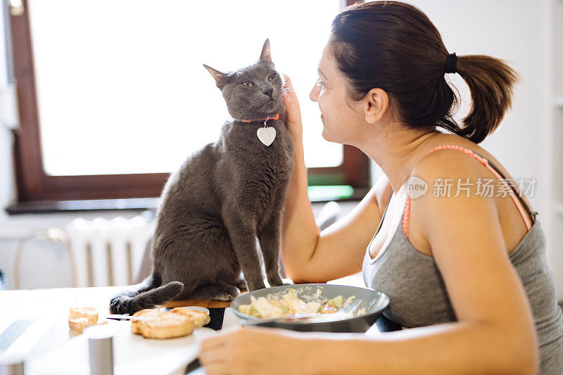 一个女人在厨房里抱着猫吃午饭