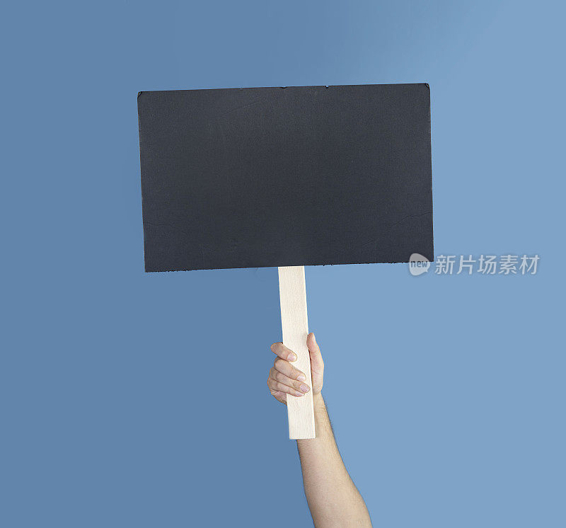 年轻女子拿着黑色的纸。女孩站在空纸板上。一个拿着空白抗议横幅的女人