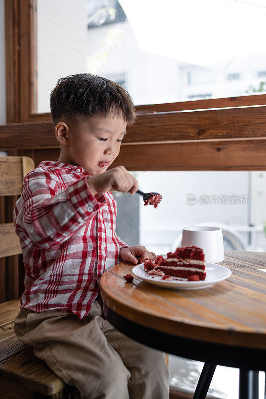 这个小男孩吃蛋糕，喝牛奶