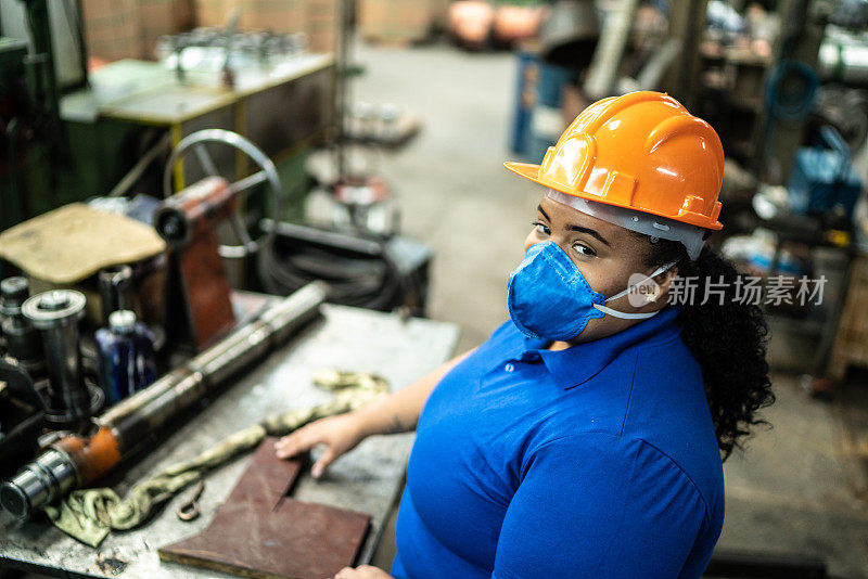 一个年轻女人在工厂检查机器零件的肖像