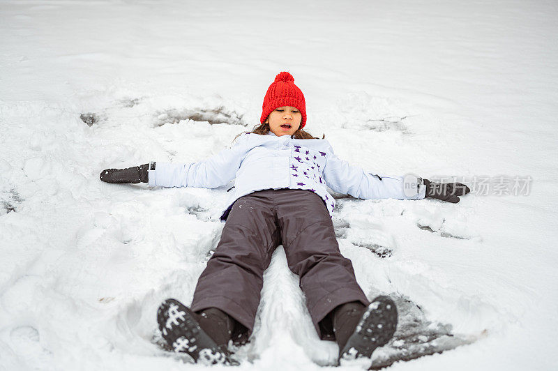 小女孩在雪地上做雪天使