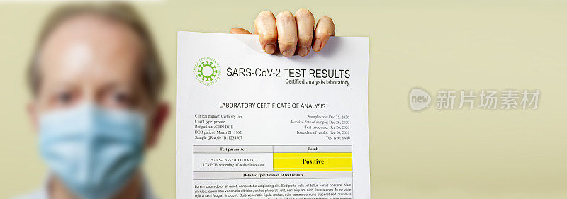 一名戴防护口罩的男子所持的导致COVID-19的SARS-CoV-2冠状病毒阳性检测结果文件
