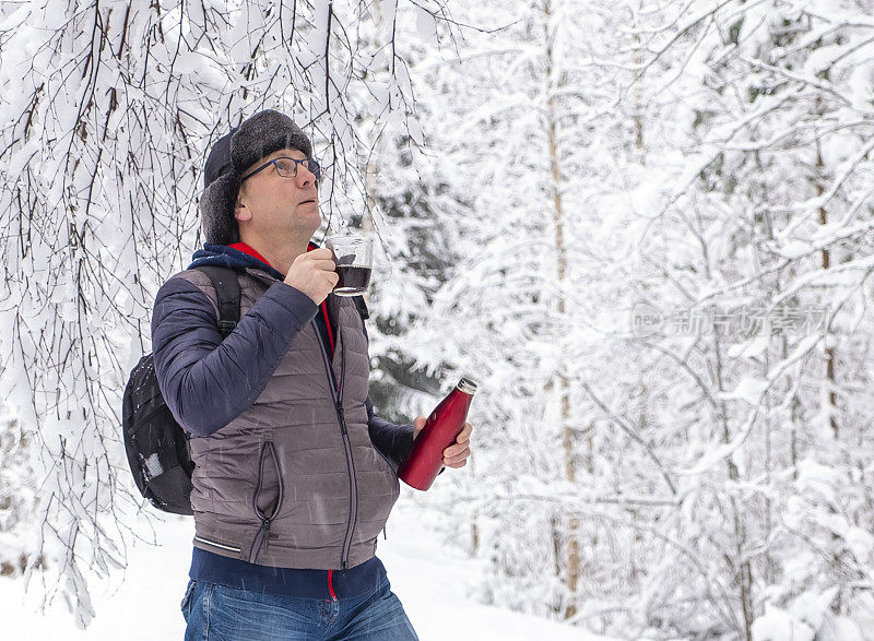 白种人在冬天的雪地里。那个人正在休息和喝咖啡。步行旅游。