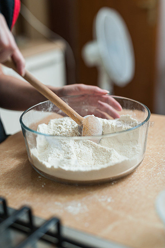 女人用木勺搅拌面粉做面团的特写镜头。
