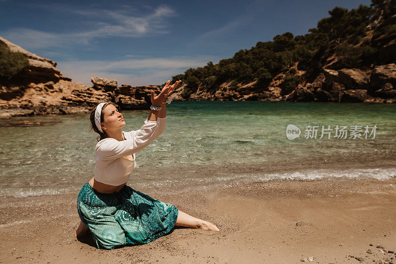 精神祈祷瑜伽女人做一个神圣的舞蹈在阳光明媚的海滩