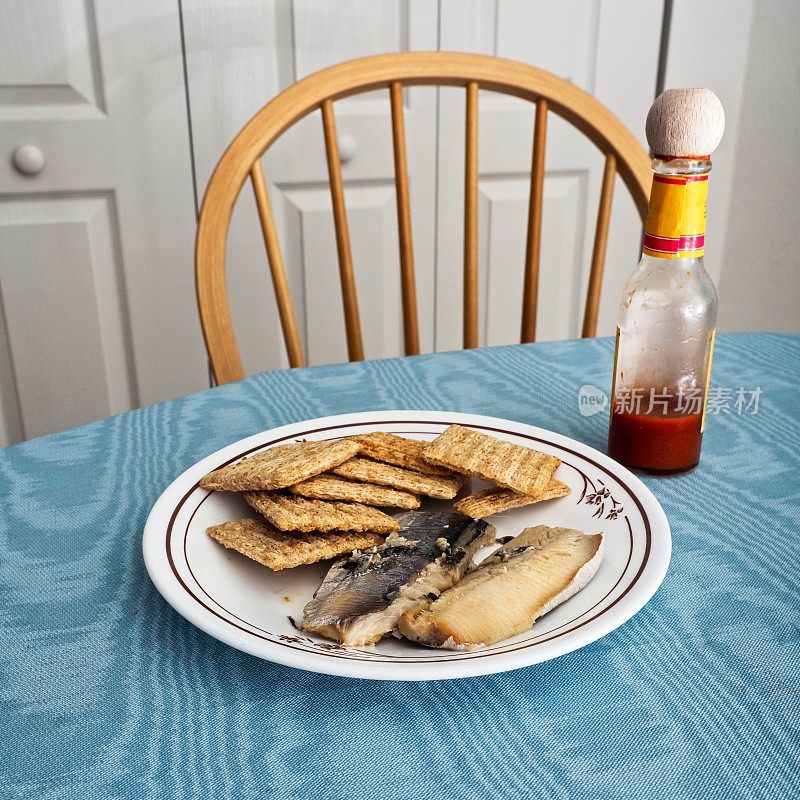 沙丁鱼和编织小麦饼干作为一种健康营养小吃与桌子，椅子，辣椒酱，和用餐区背景