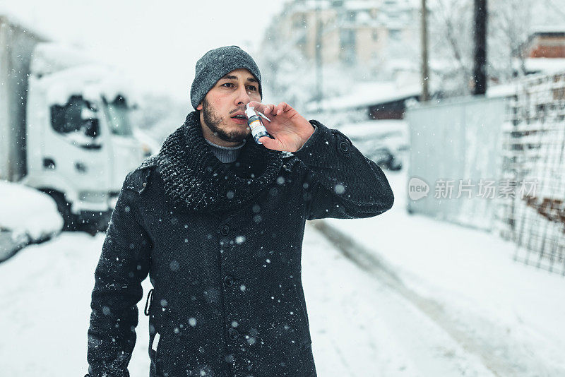 感冒和流感。一个年轻的病人在街上用喷鼻剂。