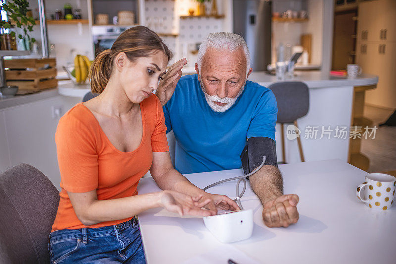 女儿在家里给父亲量血压。