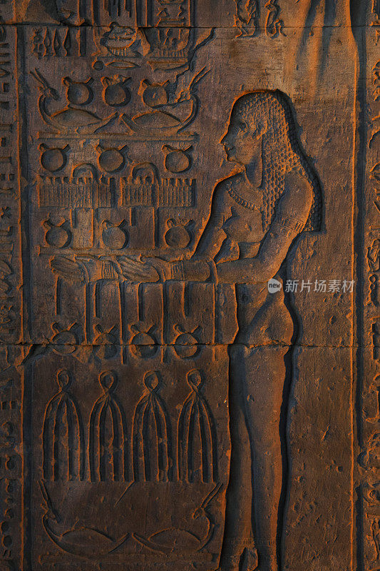 在埃及康姆博的康姆博神庙，一个女人拿着折叠的布、亚麻袋和一捆捆的象形文字皮肤
