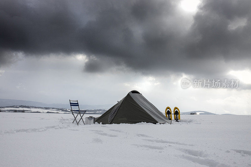 穿雪鞋，在冬山搭帐篷露营。独自一人在自然。