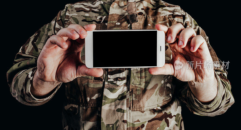 戴着手套拿着智能手机的士兵。