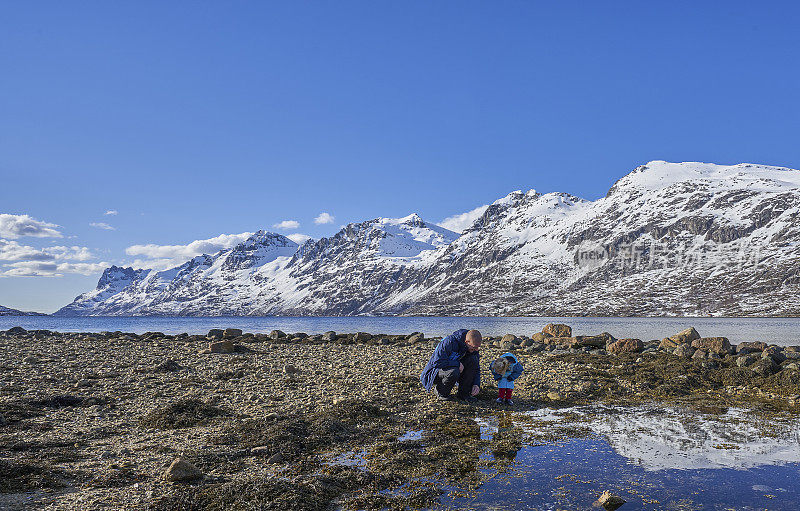 父亲和蹒跚学步的女儿在挪威特罗姆瑟附近的美丽峡湾探险