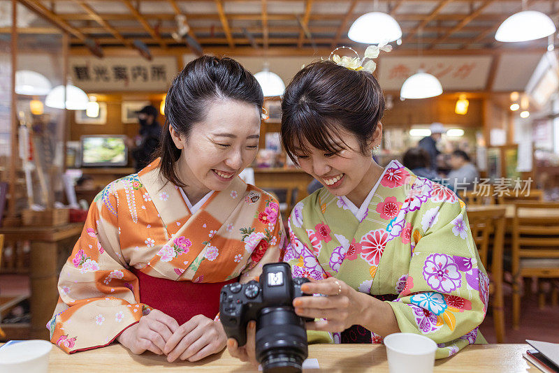 在日本传统餐厅，穿着和服的日本女性朋友在照相机前查看照片