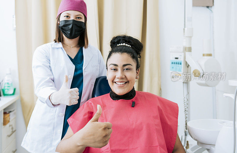 女牙医对着镜头微笑并竖起大拇指，女牙医对着病人微笑并竖起大拇指。女牙医的肖像与病人微笑的镜头在办公室
