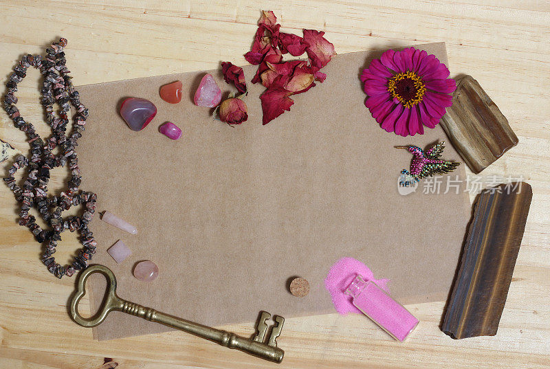 粉红色的花与粉红色的石头和黄铜钥匙在旧纸上
