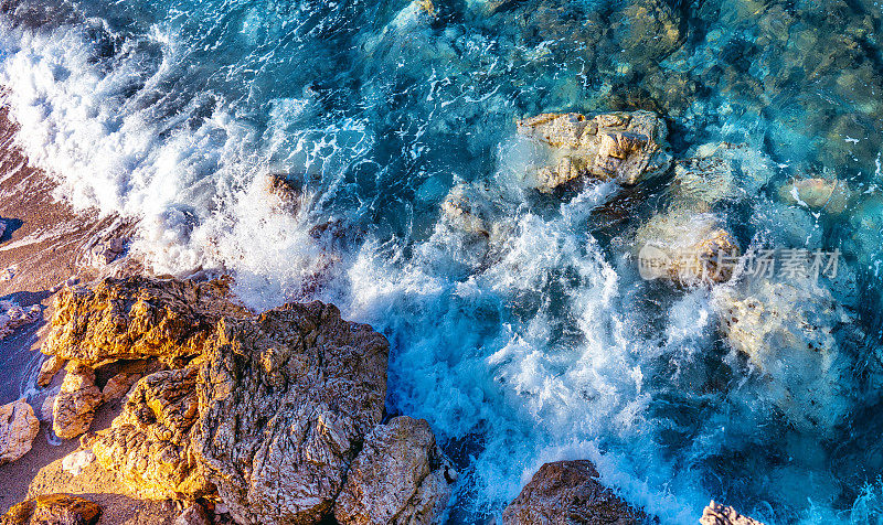 美丽的原始背景图像的透明海浪打破了岩石海岸。