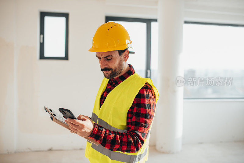 戴着防护头盔的建筑工人打电话