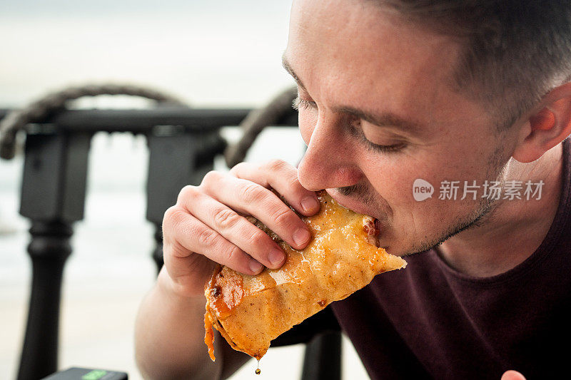 在墨西哥提华纳，二十多岁的年轻人坐在海滩边的露天餐厅吃美味的虾塔可