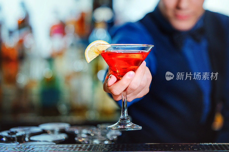 调酒师为顾客端上新鲜鸡尾酒的手