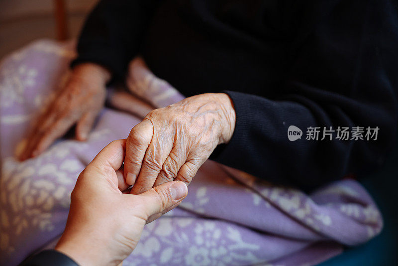 老女人的手牵着年轻女人的手，伸出援手，照顾老人的理念。