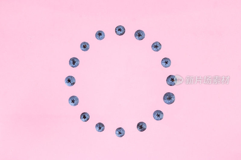 蓝莓的浆果排成一圈。粉红色的背景。
