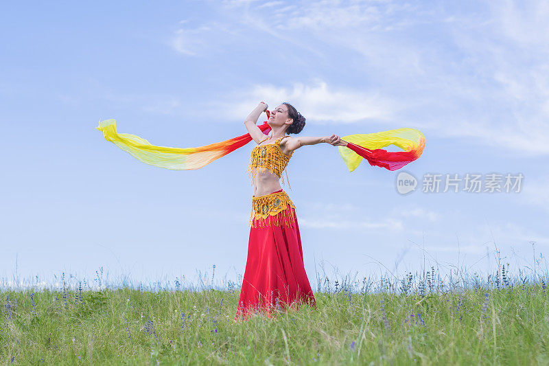 身着民族服装的年轻女子在大自然的膝上跳着东方舞蹈