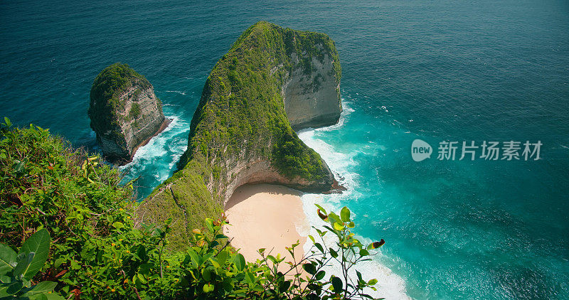 蓝色的海浪冲击着热带岩石悬崖和沙质的克林金海滩。俯瞰蓝绿色海水，巴厘岛的绿色植被。