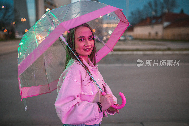 一个无忧无虑的女人在雨夜撑着伞走在腰间