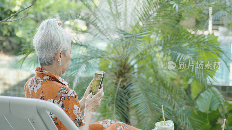在户外使用智能手机的亚洲老年妇女，银发上网者，积极拥抱科技的老年妇女
