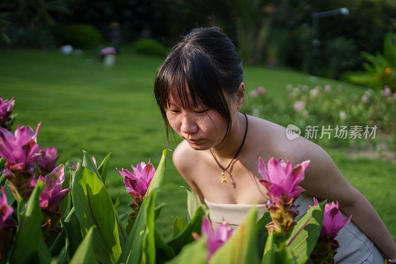 年轻女孩欣赏粉红色的花朵