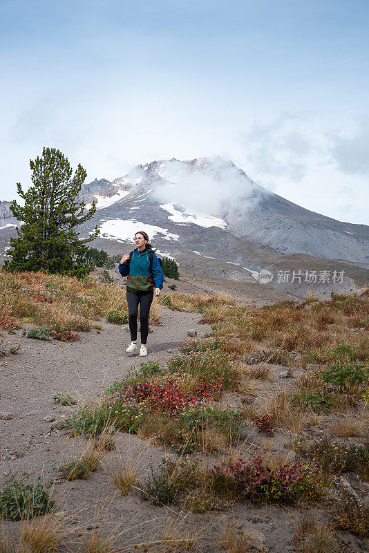 背包客妇女徒步旅行在雷尼尔山前的道路上覆盖着雪在美国华盛顿州冬天