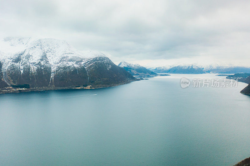 鸟瞰风景冬季日落渡轮渡海与雪山在挪威