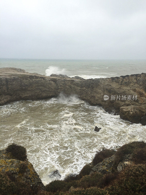 暴风雨天气中的海边悬崖。海岸线岩石，波涛汹涌的大海和多雨的天气背景