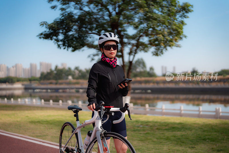 女公路自行车骑手使用智能手机