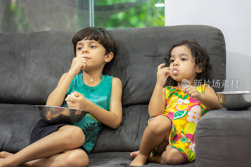 孩子们在家里看动画片和吃爆米花。