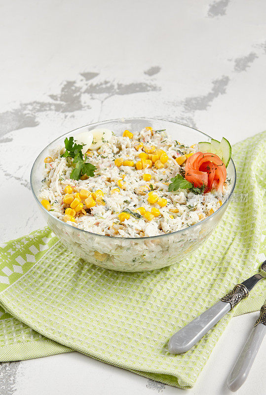 鲜蟹沙拉，配玉米，鸡蛋和黄瓜在一个透明的碗里，完美的清淡和健康的一餐